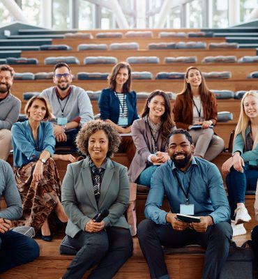 Multiracial group of happy business seminar attendees at convention center looking at camera.